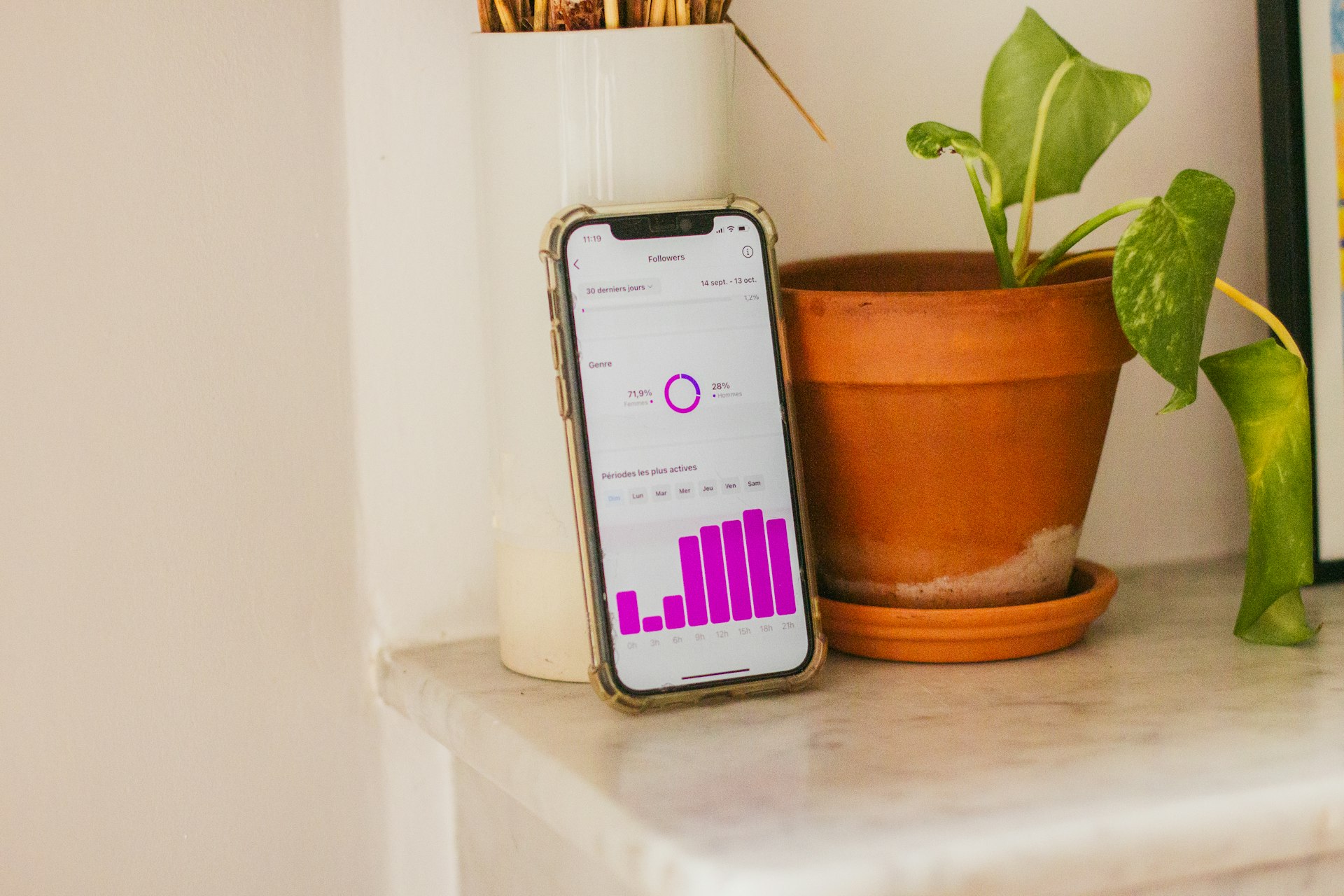 A cell phone sitting on top of a table next to a potted plant
